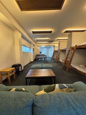 A modern interior with bunk beds, a central table, and a sofa. - East End BLD (Osaka)