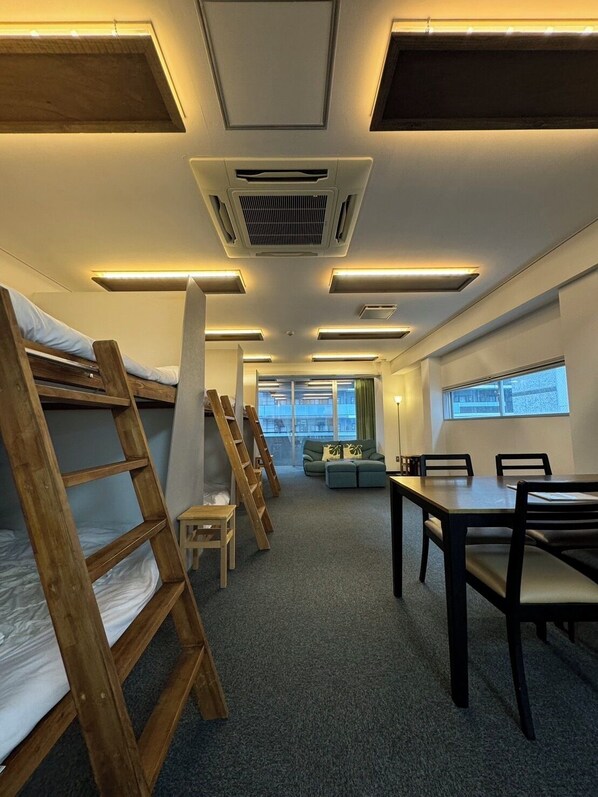 A dormitory room with bunk beds, a dining table, and a sofa. - East End BLD (Osaka)
