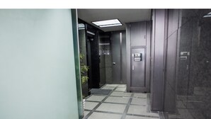 A hallway with a tiled floor, a door with a keypad lock, and a small step leading to an elevator. - Tsuboniwa apartment UTSUBO (Osaka)