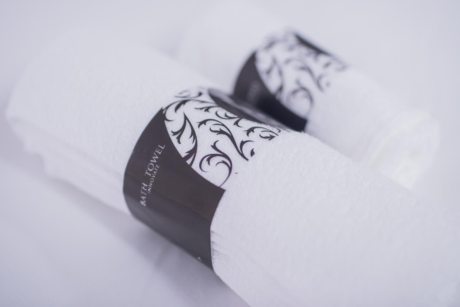 Rullalle taitettu pyyhe, jossa on koristeellinen etiketti, jossa lukee: ”Bath Towel Innovate”.