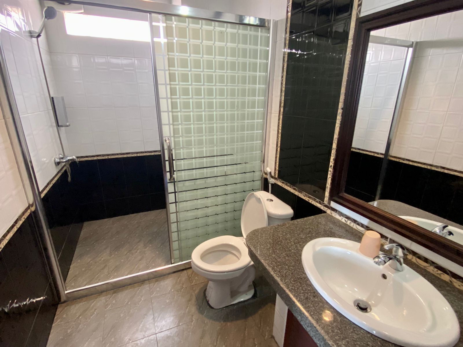 Un baño con cabina de ducha de vidrio, inodoro y lavabo con espejo.