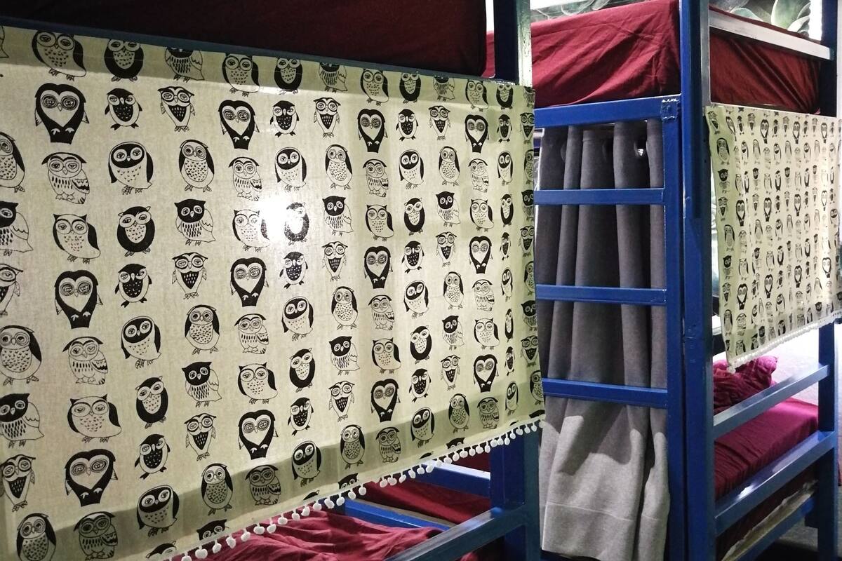Tweepersoonsbed met beddengoed met een patroon, een zichtbare airconditioning en een betegelde vloer.