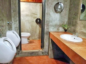 A men's restroom with three urinals, a toilet, and a sink with a mirror above it.