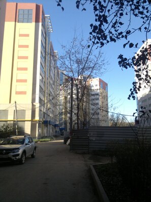 Urban building with a combination of yellow and white facades, featuring a metal gate entrance and a paved area.