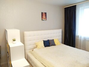 Relax in a serene space with a plush bed, a potted plant, and a framed Eiffel Tower view.
