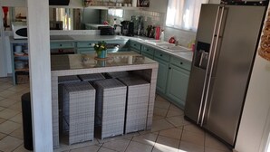 Cuina amb una illa central, un refrigerador i un microones.
