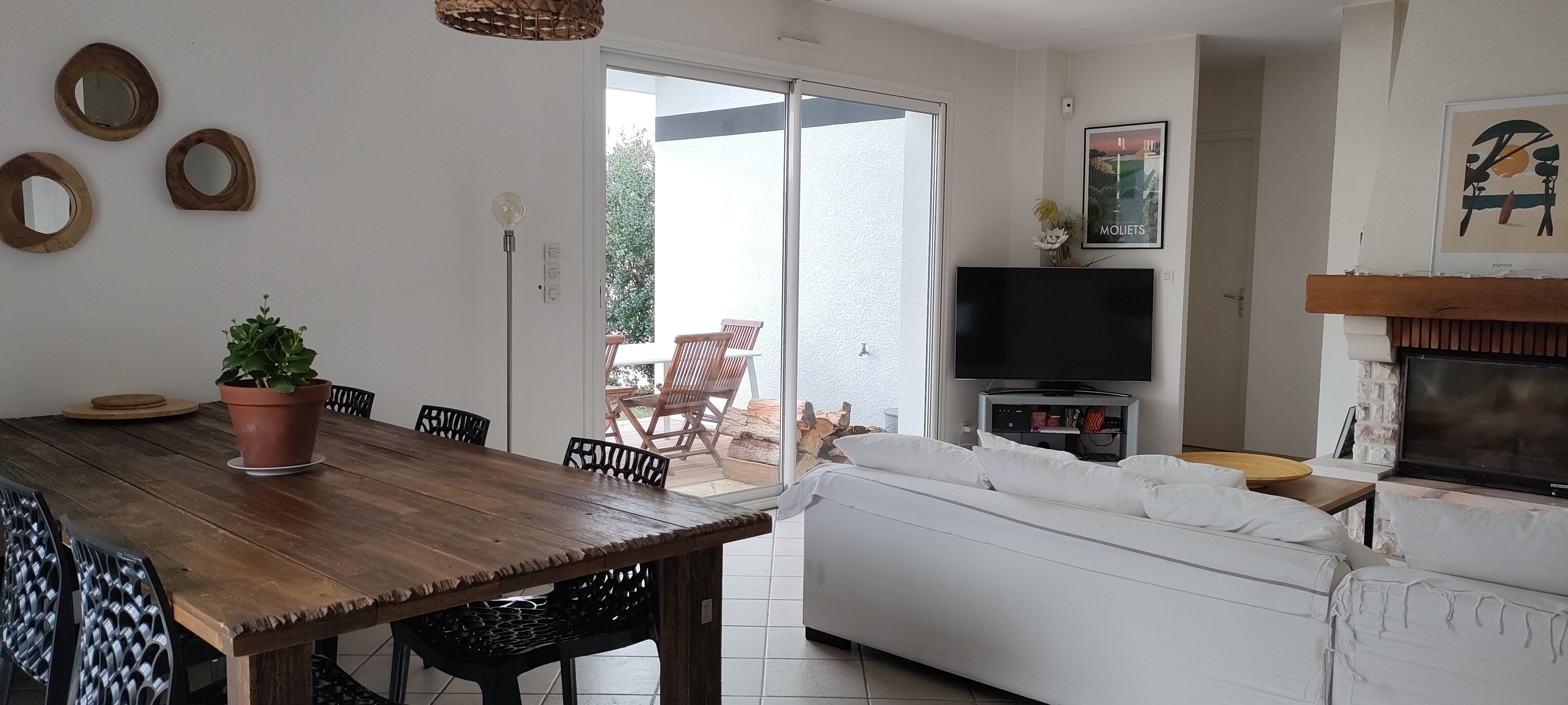 Een eetgedeelte met een houten tafel en stoelen, een potplant en een televisie op de achtergrond.