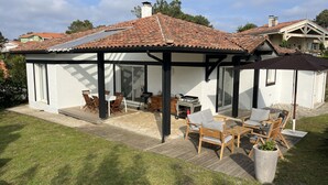 Un porxo cobert amb mobiliari exterior, una barbacoa i una pèrgola.
