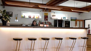 A bar area with a counter, stools, and various bottles and glasses. - Hotel Rohanov (Vacov)