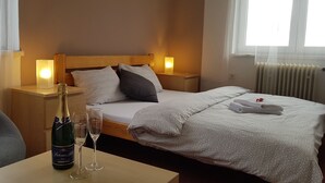 A hotel room with a bed, two bedside tables with lamps, a bottle of champagne, and two glasses on a small table. - Hotel Rohanov (Vacov)
