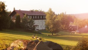 A large house with a red roof, surrounded by a grassy field and trees. - Hotel Rohanov (Vacov)