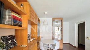 A modern kitchen with wooden cabinets, a white dining table with four chairs, and a pendant light.