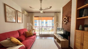 A living room with a red sofa, a TV, a wooden cabinet, and a ceiling fan.