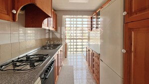 A kitchen with wooden cabinets, a stainless steel sink, and a gas stove.