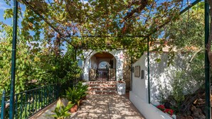 A covered walkway with potted plants, a white wall, and a view into a building. - Jurinea House Lift with private pool (TORRES)