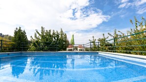 A swimming pool with two lounge chairs and a sun umbrella, surrounded by greenery and a clear sky. - Jurinea House Lift with private pool (TORRES)