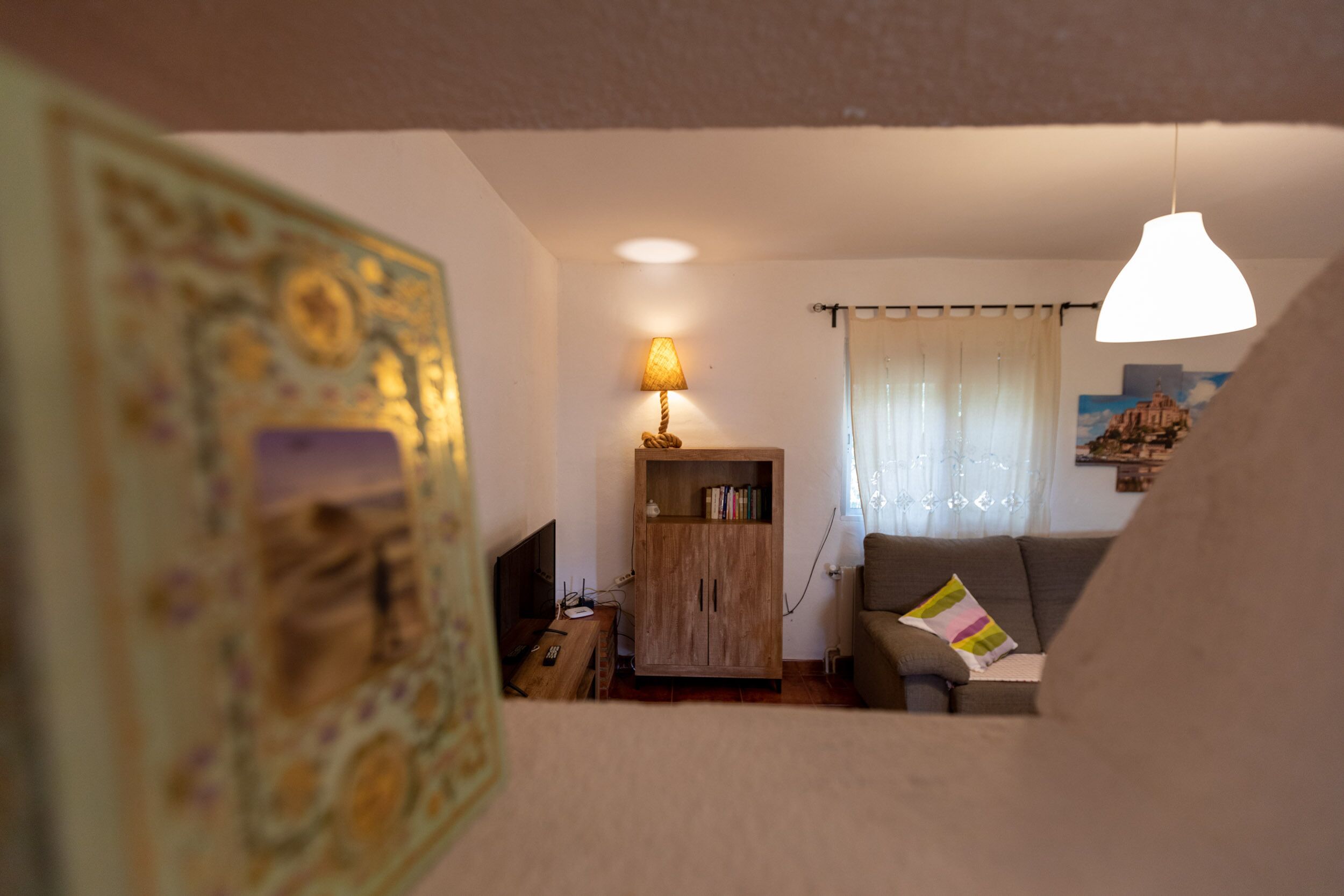 A cozy living room with a wooden cabinet, a sofa, a lamp, and a painting on the wall.