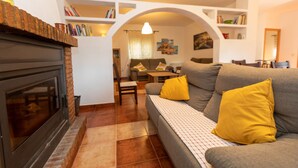 A cozy living room with a fireplace, a sofa with yellow cushions, and a bookshelf filled with books. - Jurinea House Lift with private pool (TORRES)