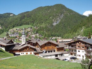 A mountainous village with traditional wooden houses, a church, and a clear view of the surrounding forest. - Cozy studio 4 pers, ski-in/ski-out, terrace, garage, WIFI (La Clusaz)
