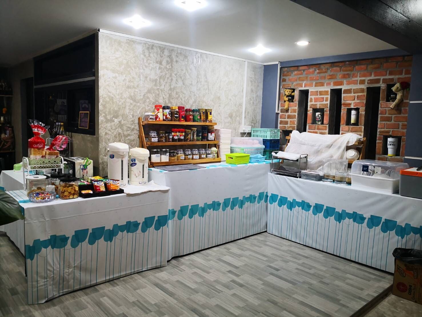 Un área de recepción con mostrador, exhibición de bocadillos y condimentos, y pared de ladrillo de fondo.