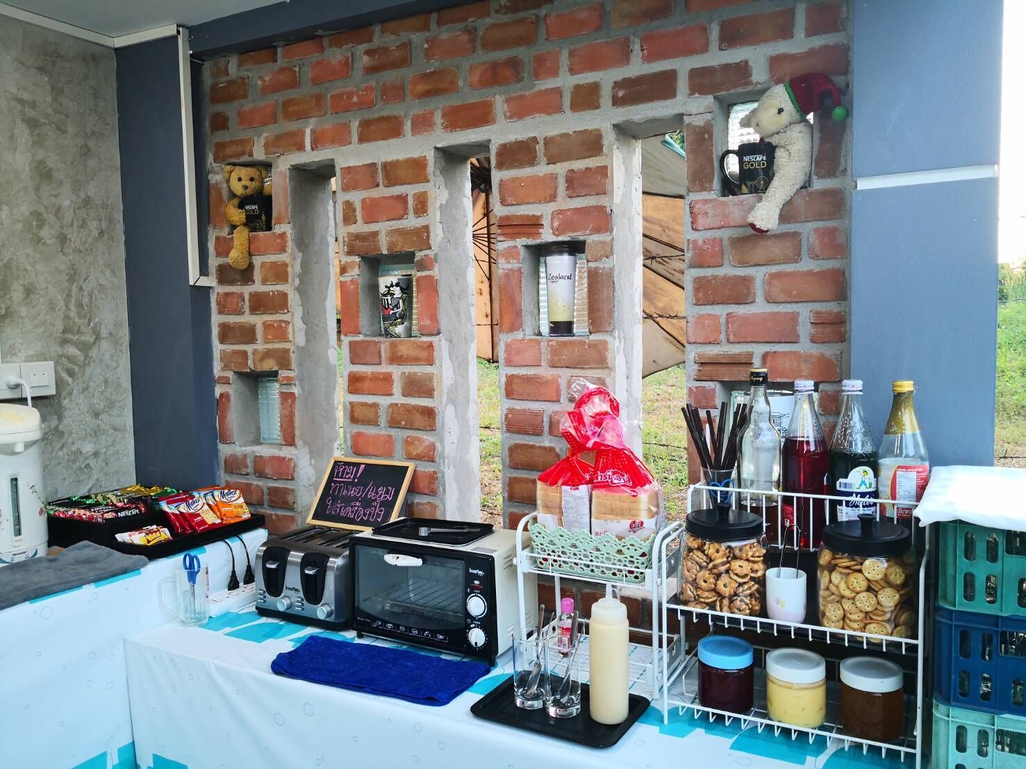 A breakfast setup with a toaster, kettle, and various food items on a table.