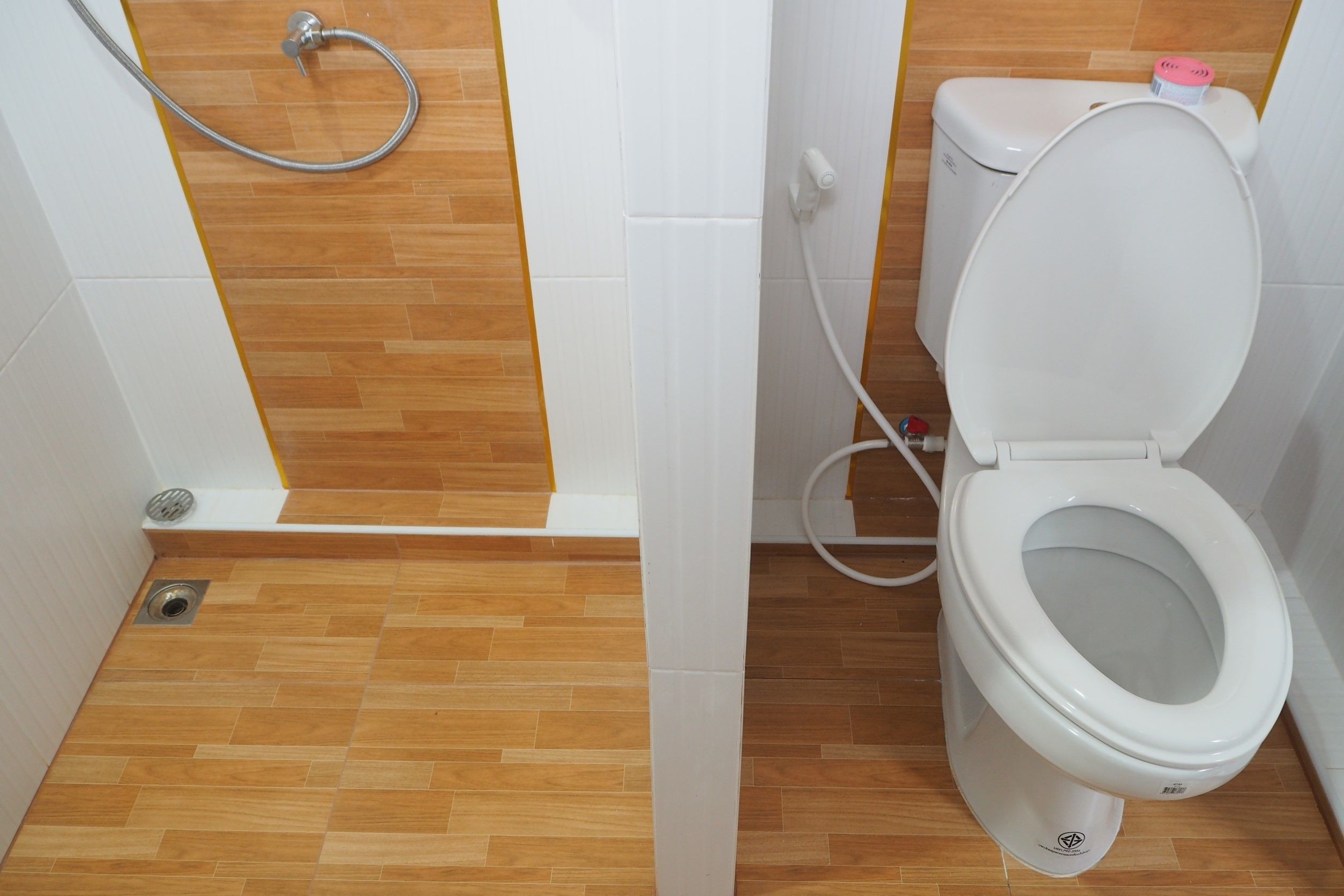 A bathroom with a toilet, a shower, and a wooden floor.