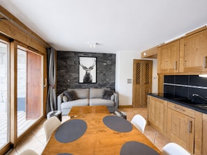 Une cuisine moderne avec des meubles en bois, un plan de travail noir et un mur en pierre orné d’une œuvre d’art représentant un cerf.
