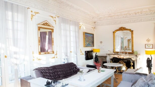 A luxurious room with a large bed, a white vanity, a fireplace, and ornate gold detailing on the walls and ceiling. - Villa Ananda Huo (Saint-Cloud)