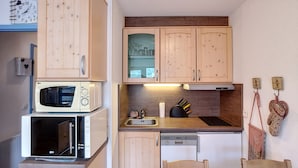 Eine kleine Küche mit Holzausstattung, einer Mikrowelle, einem Toaster und einem Spülbecken.