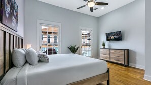 A bedroom with a bed, a ceiling fan, a TV, and a view of the outside. - 15% OFF Monthly | 10% OFF Weekly-Urban Oasis 4BD House close to FQ & City Hot Spots (New Orleans)