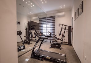 A home gym with a treadmill, stationary bike, and weight bench. - 1920s Boutique Hotel and Restaurants (Cairo)