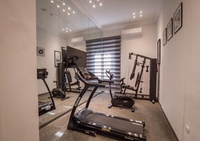 Un gimnasio en casa con cinta de correr, bicicleta estática y banco de pesas.