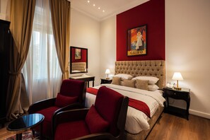 A hotel room with a bed, two nightstands, a desk, two chairs, a red wall, and a window with curtains. - 1920s Boutique Hotel and Restaurants (Cairo)