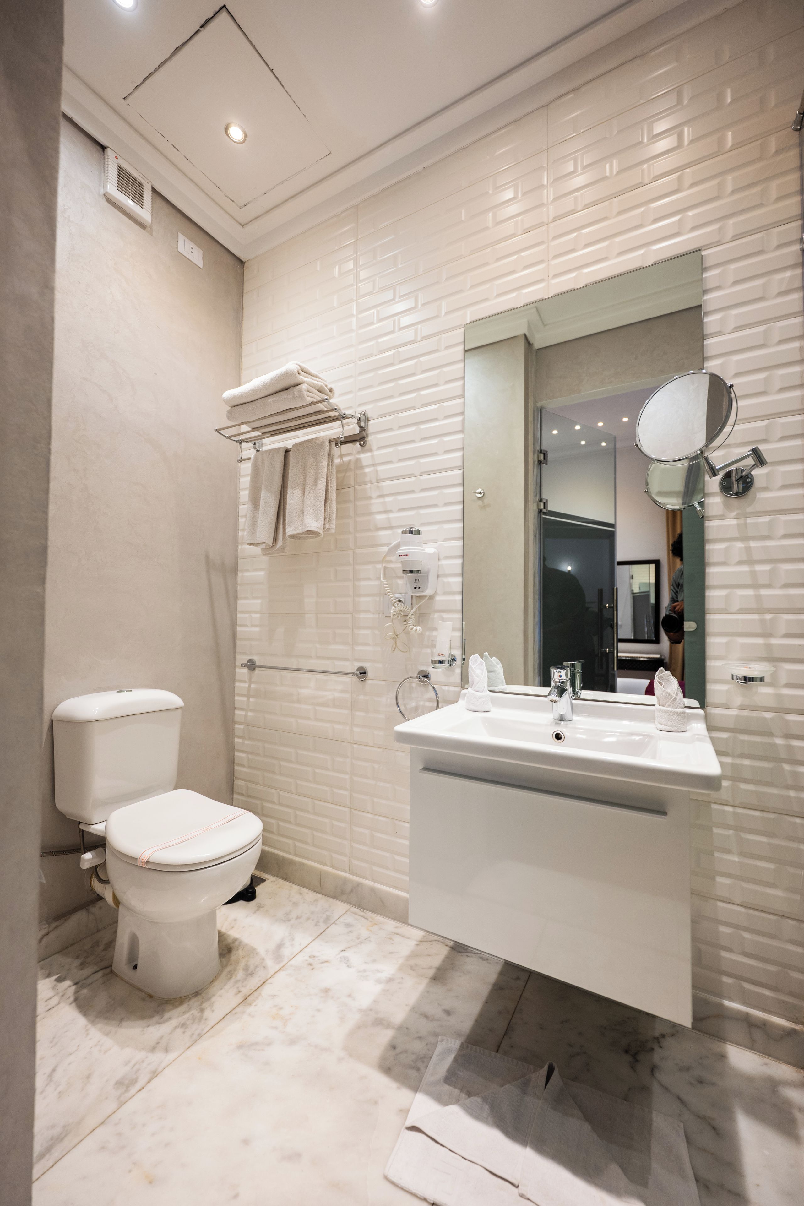A modern bathroom with a toilet, sink, and mirror.