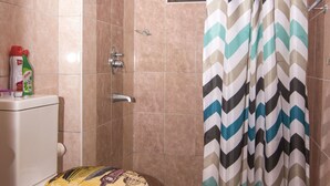 A bathroom with a toilet, shower curtain, and slippers on the floor. - Cozy Nest (Nairobi)