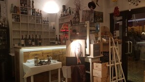 Un coin bar avec des étagères remplies de bouteilles et de verres, une table avec une chaise et un escabeau.