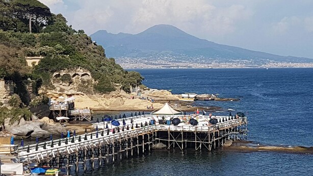 Une jetée qui s’avance dans la mer, avec une chaîne de montagnes en arrière-plan.