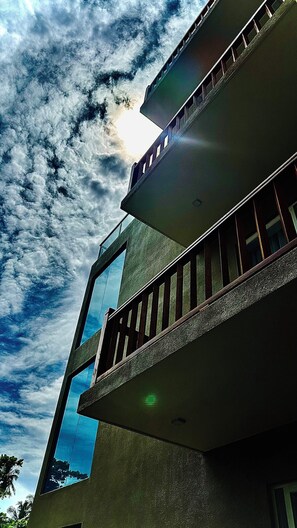 Un edificio de varios pisos con un balcón y un ventanal grande.