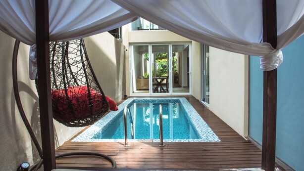 A pool area with a hanging chair, a wooden deck, and a glass door leading to an outdoor space. - Kings Landing Unawatuna (Unawatuna)