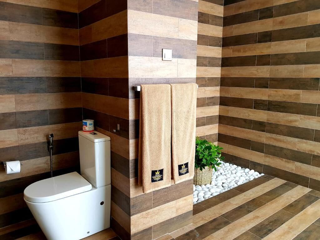 Un baño moderno con inodoro, dos toallas y una planta pequeña.