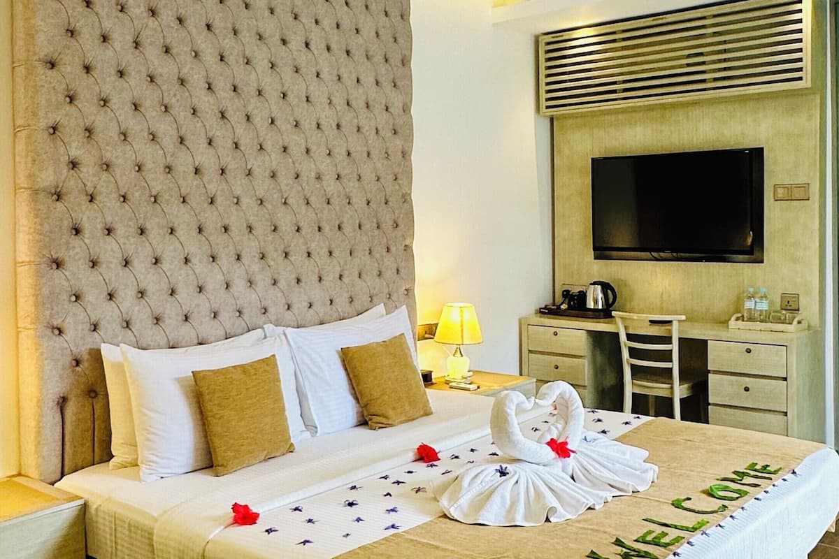 A modern hotel room with a large bed, a desk, a television, and a unique ceiling fan.