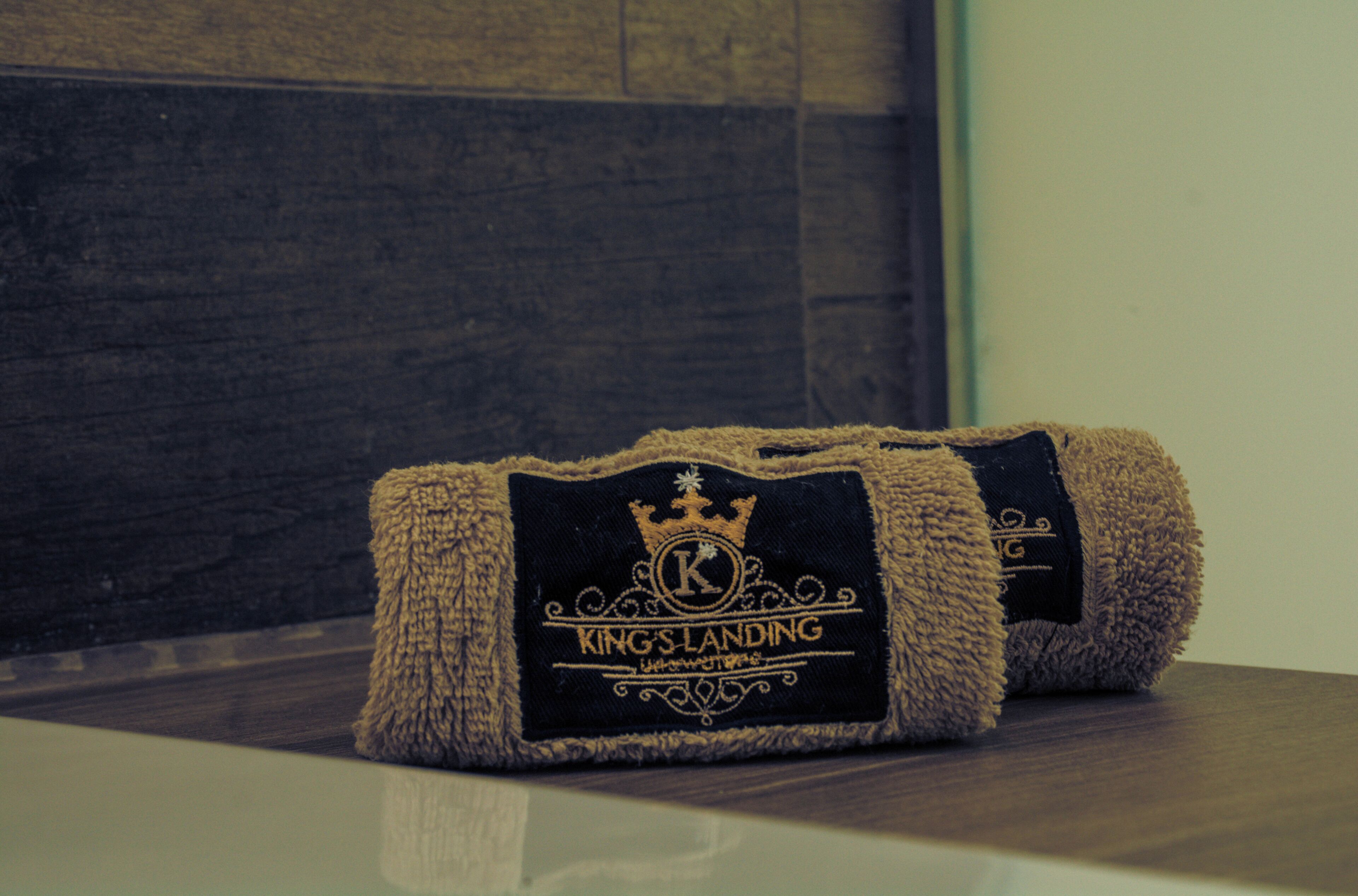 A rolled-up towel with a 'Kings-Landing' label on a wooden surface.