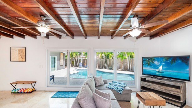 A living room with a gray sofa, wooden coffee table, and a TV on a wooden stand. - House - Miami pool house, near Miami Int Airport and attractions. (Miami Springs)