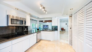 A modern kitchen with white cabinets, a stainless steel microwave, and a granite countertop. - House - Miami pool house, near Miami Int Airport and attractions. (Miami Springs)
