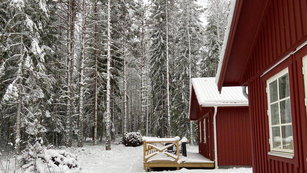A cabin with a wooden deck and a snow-covered porch.