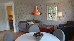 A living room with a sofa, a coffee table, and a dining table with a bowl of pinecones.