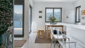 Una cucina moderna con vista sul mare, un tavolo di legno e una sedia bianca.