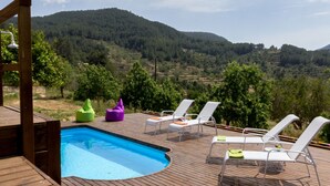 A wooden deck with a swimming pool, lounge chairs, and a view of a mountainous landscape. - Typical Ibizan country house with private pool in a beautiful protected environment! (ISLAS BALEARES)