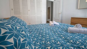 A bedroom with a bed, white wardrobe, and a mirror on the wall. - La Galeria de San Antonio (Cádiz)