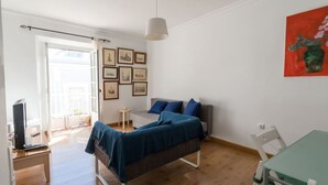 A bedroom with a bed, a desk, a chair, a TV, and a window. - La Galeria de San Antonio (Cádiz)